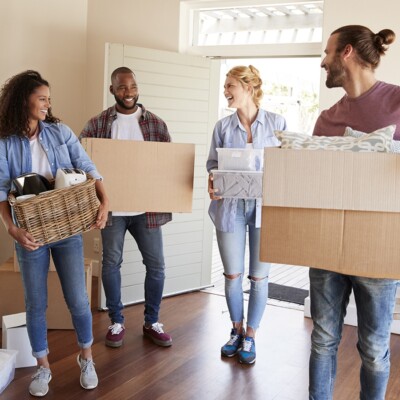 Friends help a couple to carry boxes into new home on moving day.