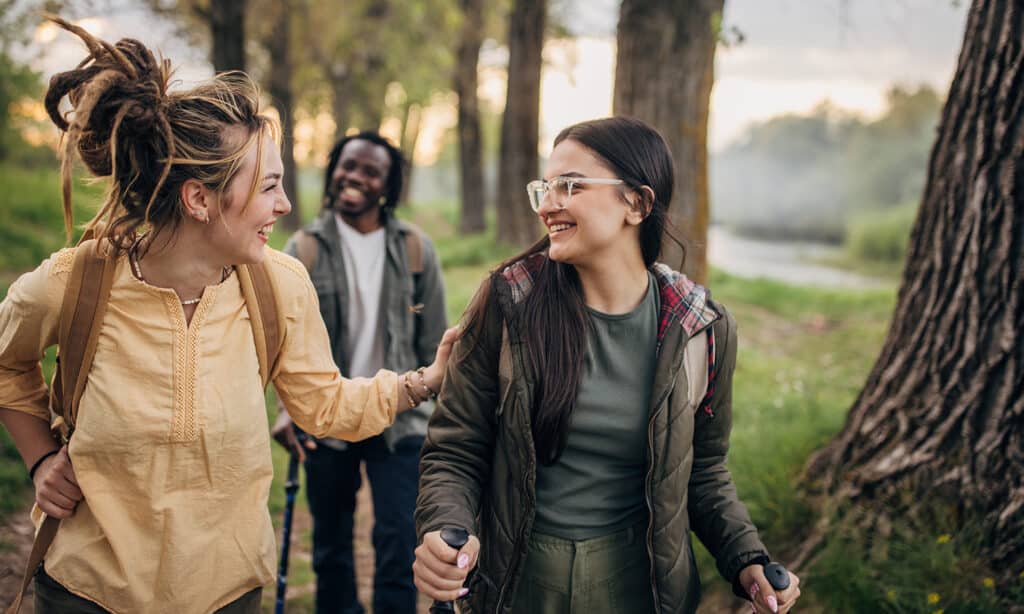 Three people, man and two women hikers taking a walk in nature together.