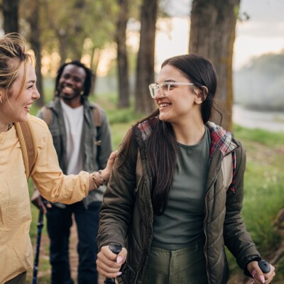 Three people, man and two women hikers taking a walk in nature together.