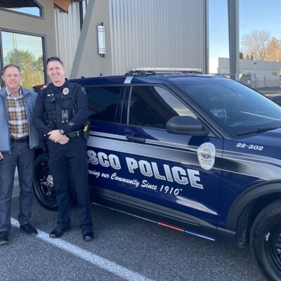 A group of Navigators first responders stand in front of a police cruiser while smiling for a photo.