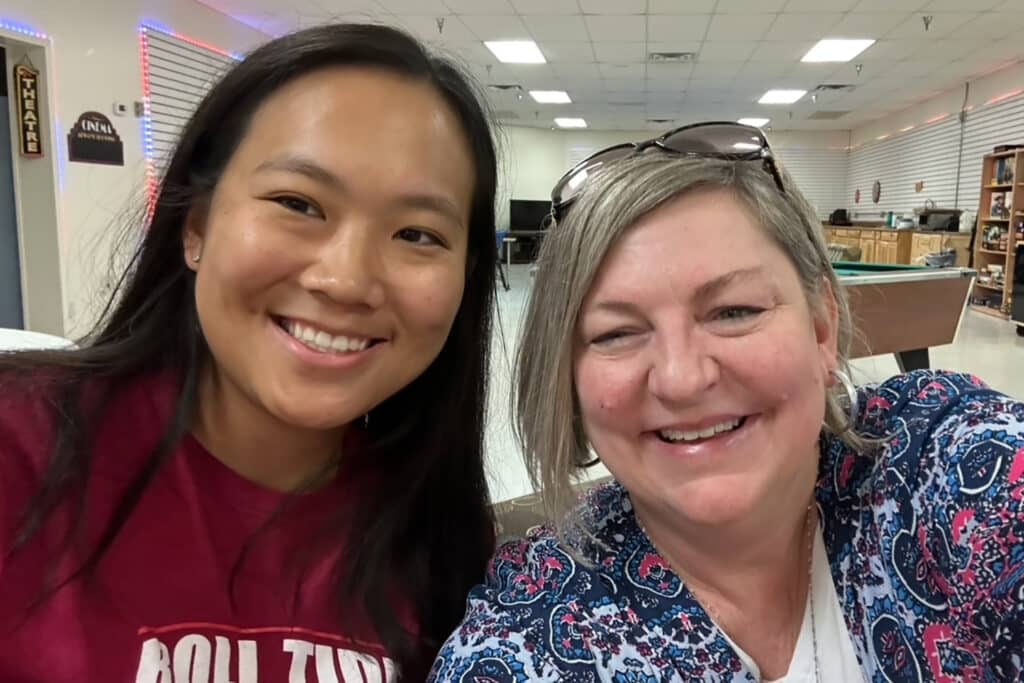 Two women smiling for a selfie indoors.