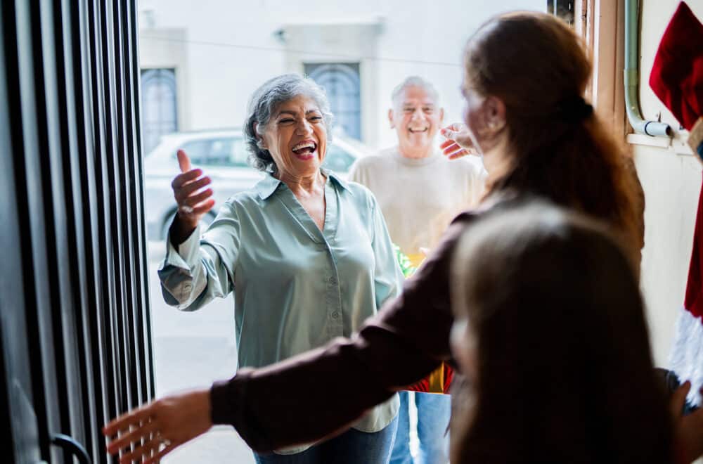 Older couple joyfully greeting family at the door.