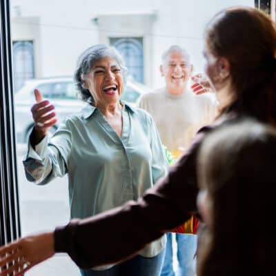 Older couple joyfully greeting family at the door.