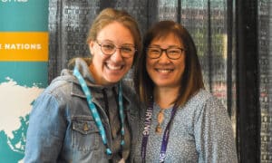 Two women embrace each other and smile at the camera.