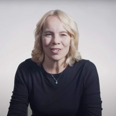 Vicki Gatchell speaking while sitting at a table with a white background.