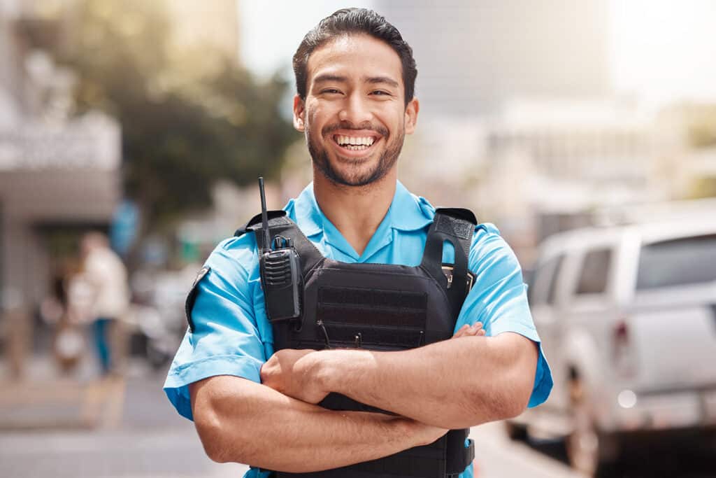 A police officer stands in front of a blurred city landscape.