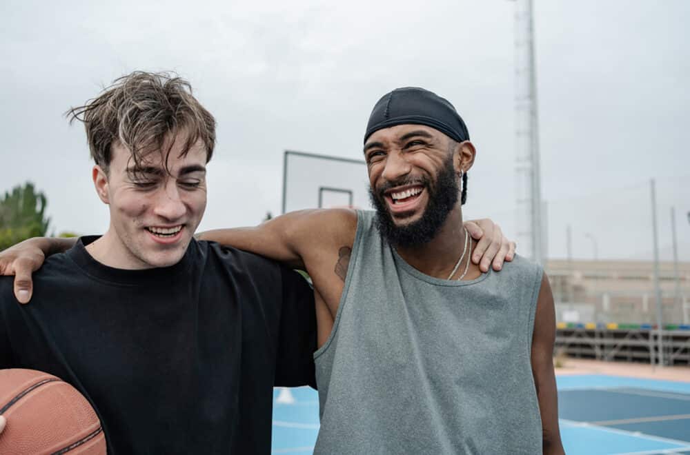 Two basketball players are laughing together after a game on a sunny day