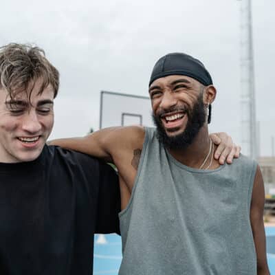 Two basketball players are laughing together after a game on a sunny day